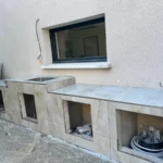 Création d’une cuisine d’été en maçonnerie avec pose de carrelage, adaptation plomberie et électricité, installation d’évier inox et pose d’auvent à Saint-Genis-Pouilly