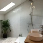 Rénovation de salle de bains avec redistribution des volumes, travaux de plomberie, pose de faïence murale, WC suspendu et meuble vasque double à Versonnex